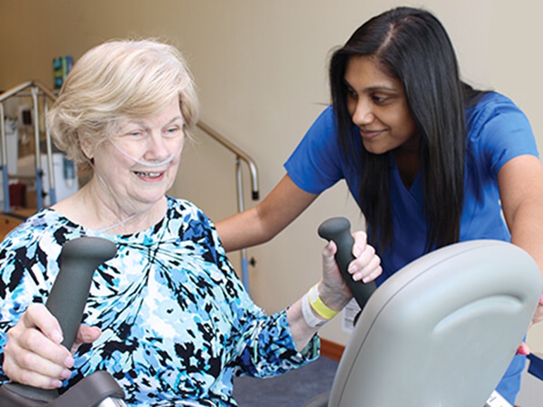 Cardiac patients does exercises on an elliptical during rehabilitation therapy session. 