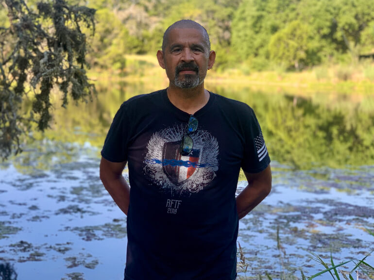 Abel Garza posing for a picture in front of a stream after his recovery.