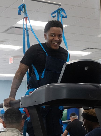 Photo of Z McKinney using a harness to walk on a treadmill at Baylor Scott & White Institute for Rehabilitation. 