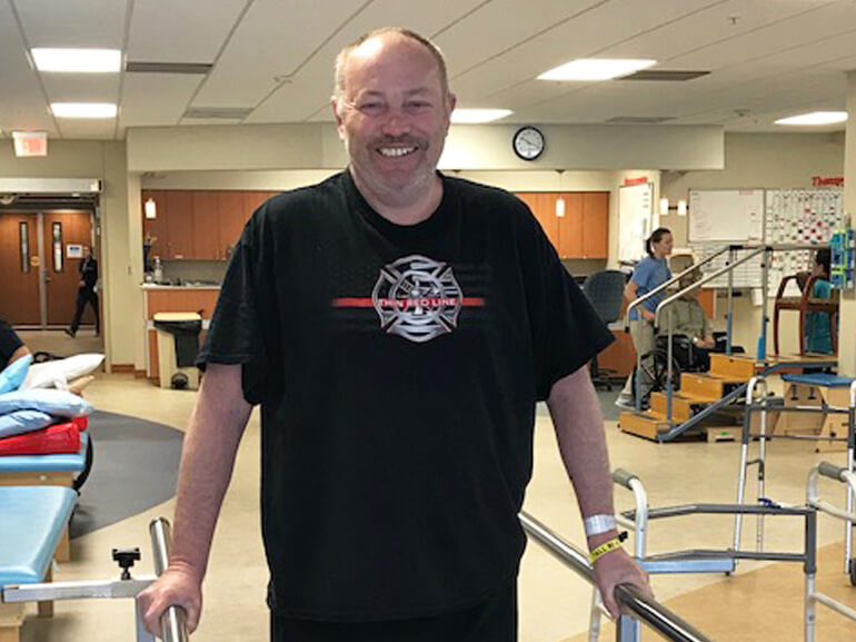 Charles using parallel bars in the gym for walking therapy.