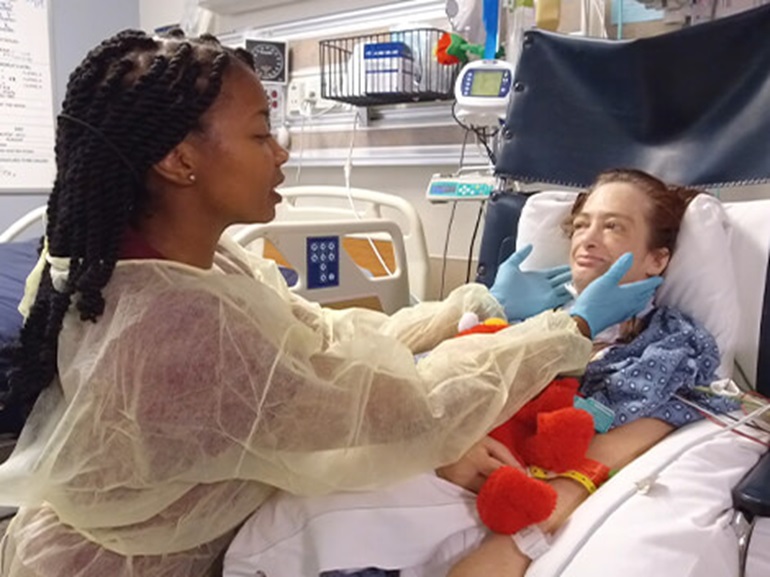 Therapist examines patient laying in bed.
