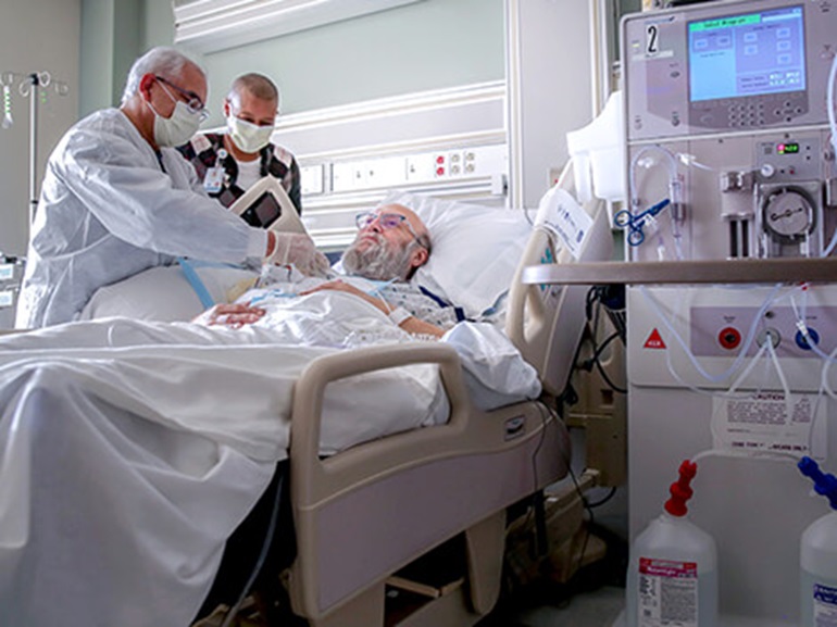 Care team examines patient as the patient is lying in bed.