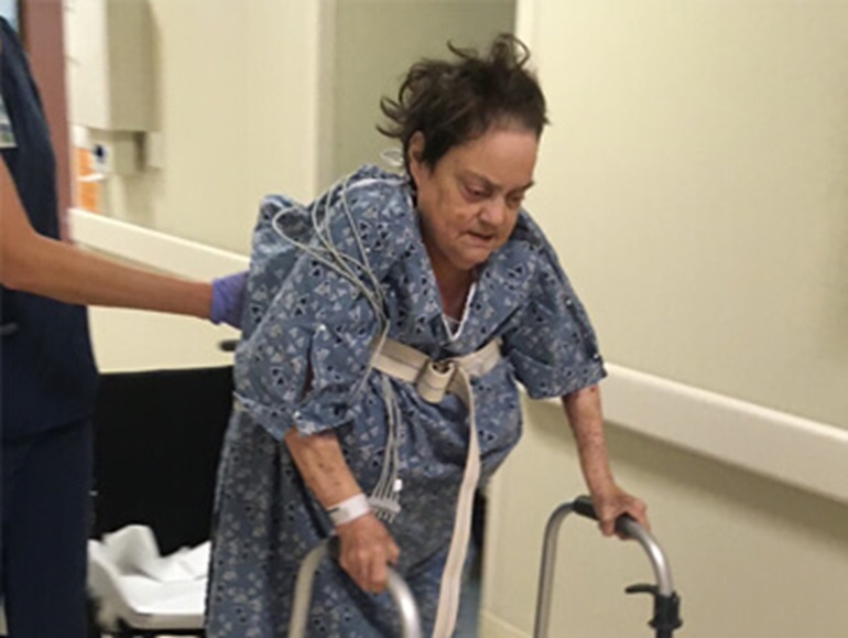 Margaret Shaw balancing on her walker with the help of her therapist in the hospital. 