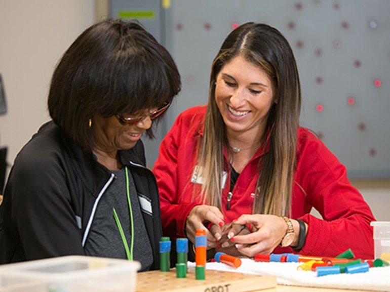 Stroke recovery patient preforms motor function exercises with therapist.