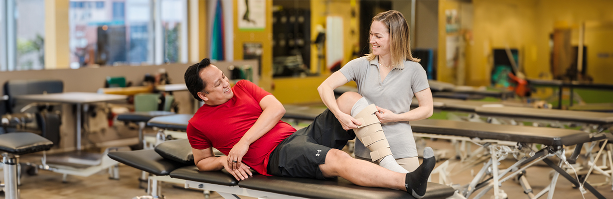 A female physical therapist wrapping a patient's leg in exercise bandage.