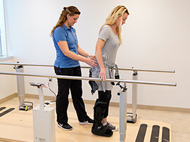 Orthopedic patient with a leg injury walks with therapist's help.
