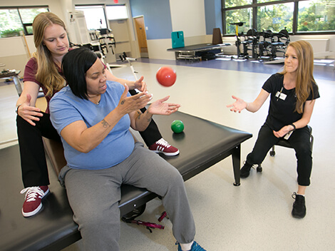 Physical therapists help patient with exercises.