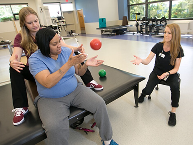 Physical therapists help patient with exercises.
