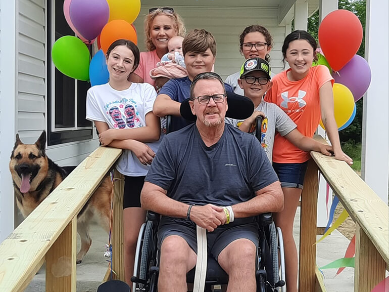 Dean Eying, sitting in a wheelchair, surrounded by his family.