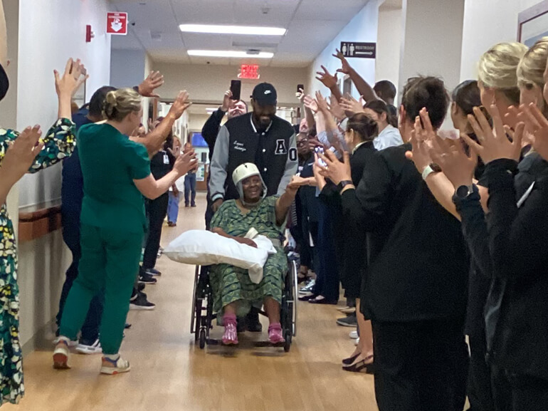 Shaunt is pushed down the hospital hallway while her care team stands on both sides celebrating.