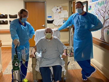 Rabbi Larry Heimer sitting in his wheelchair for a picture with his care team. 