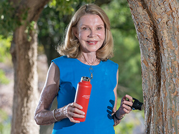 Carol walking outside holding a red water bottle in her hand.