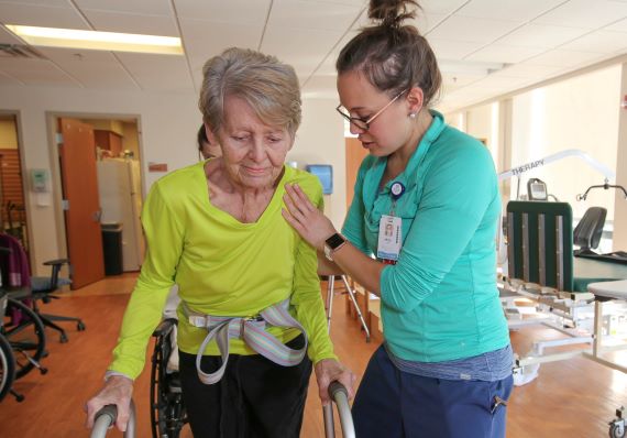 A patient uses a walker to learn to walk again following cardiac surgery.