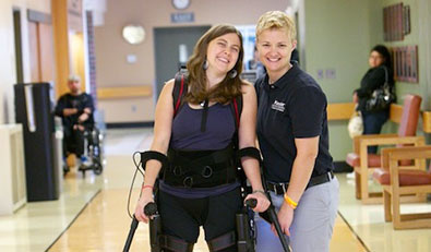 Patient walking with crutches smiles while physical therapist helps steady her.