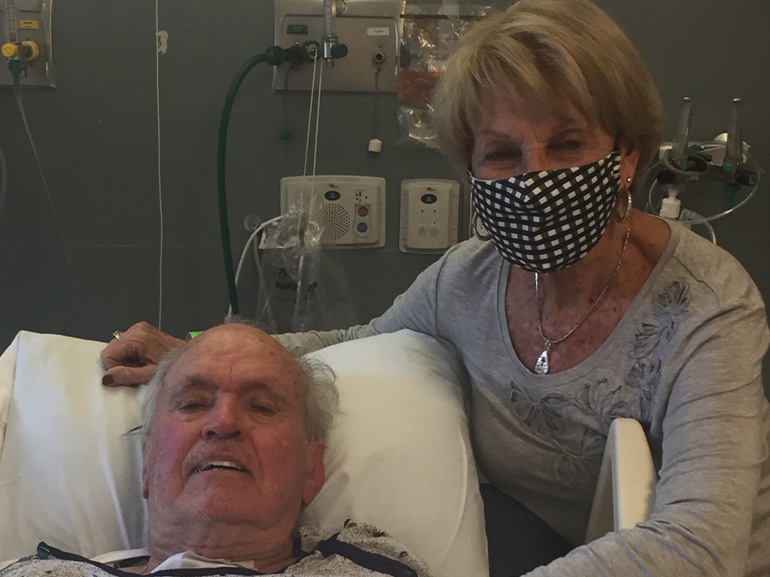 Bill Young laying in hospital bed with his wife beside him.
