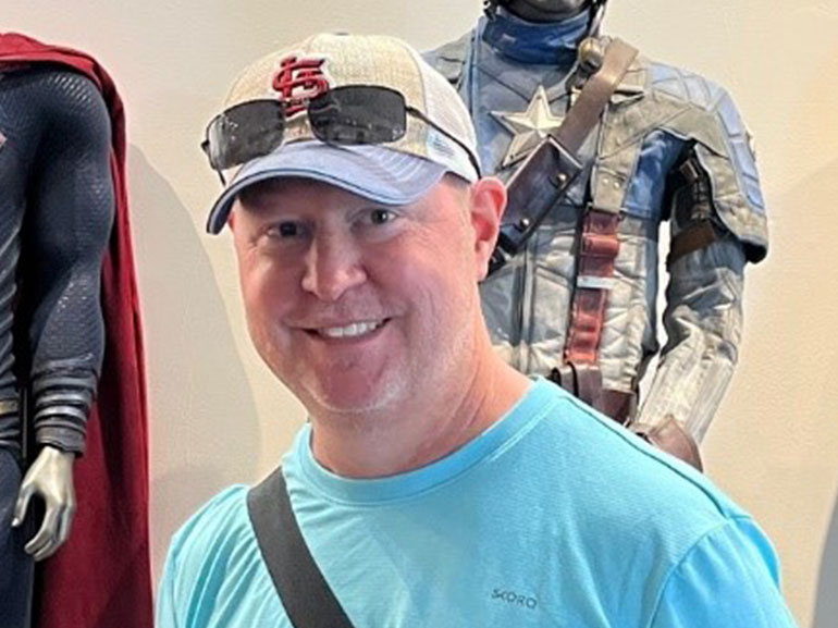 Stephen Allbright standing wearing a hat and blue shirt. 