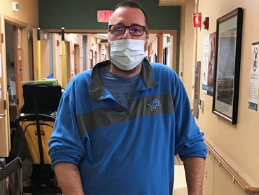 Steven Peterson standing and wearing a mask in a hospital hallway.