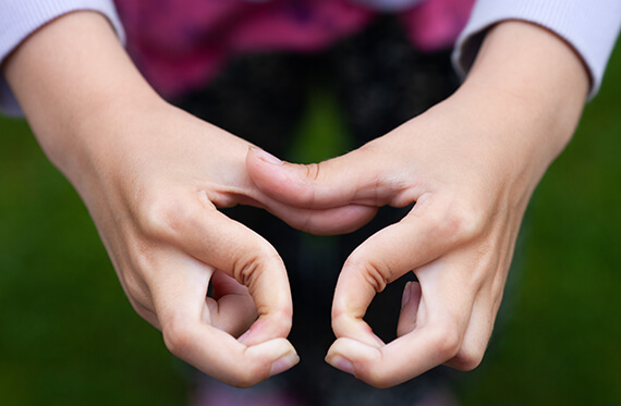 Close up image of hands held together while bending fingers into circles.