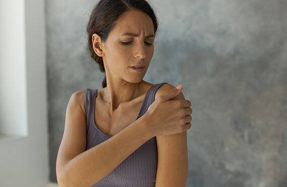 Woman holding her shoulder with painful expression.