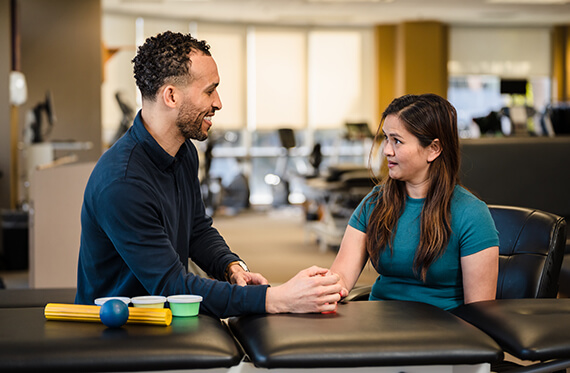 A therapist and patient sitting next to each other and talking while there are hand therapy tools beside them