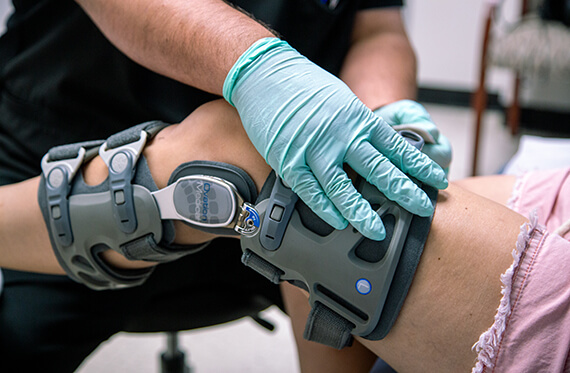 Close up of a physical therapist adjusting a knee brace on a patient