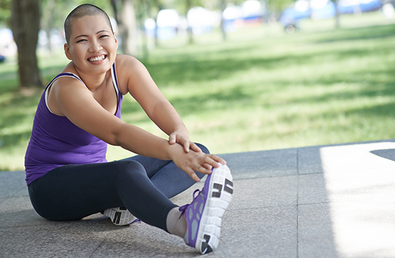 Woman sitting on the floor while stretching her legs and wearing workout clothes