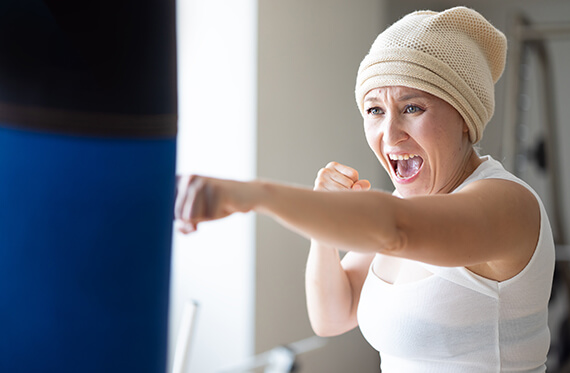 A close up of a woman is wearing a beanie and punching a punch bag