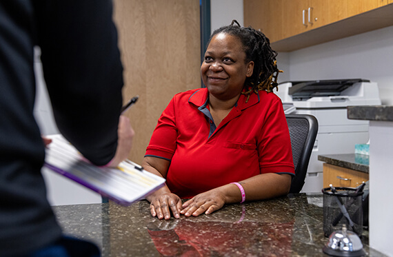 Receptionist sitting at a front desk while a patient is signing paperwork in front of her