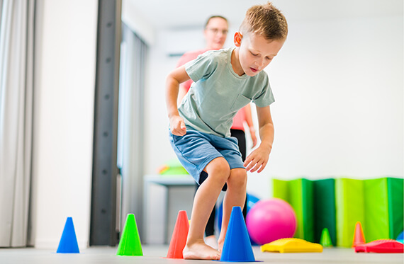 A young boy jumping over an obstacle course made with cones 