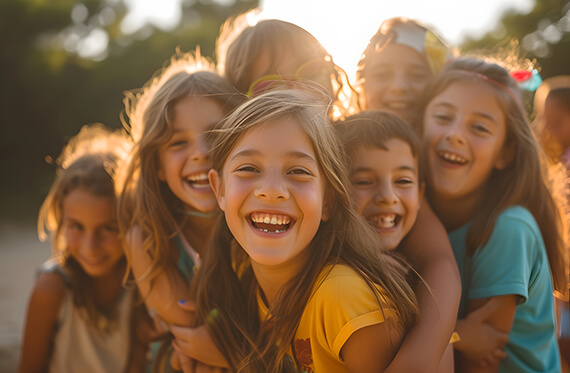 A group of kids hugging and smiling at the camera